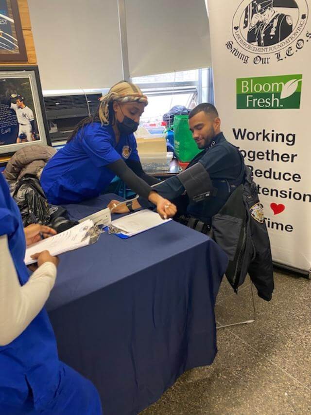Volunteer checking a man's blood pressure at a screening table