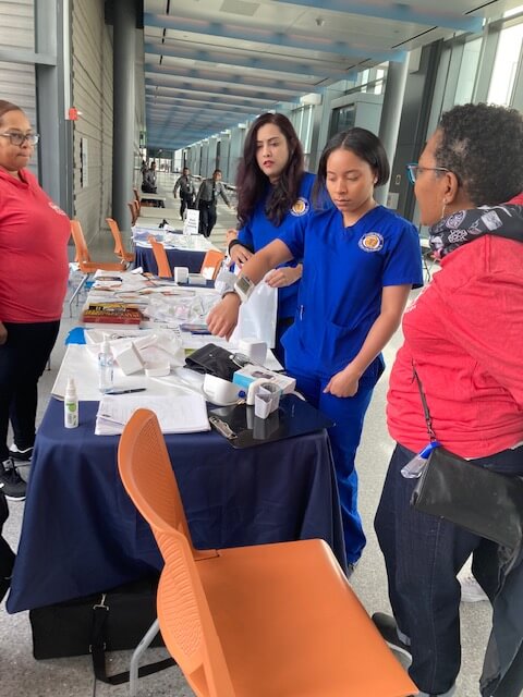 Nurses in blue scrubs at a screening table