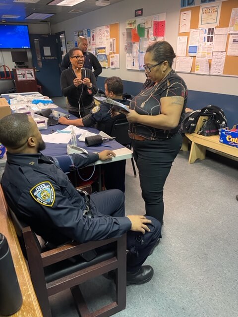 Volunteer screening an officer in a station room