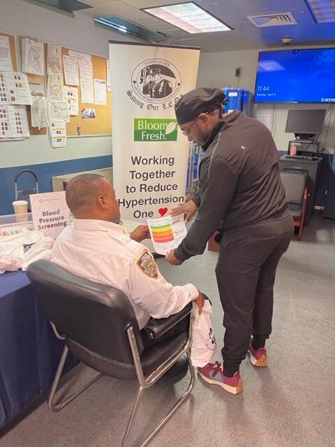 Volunteer checking a seated man's blood pressure in a station room