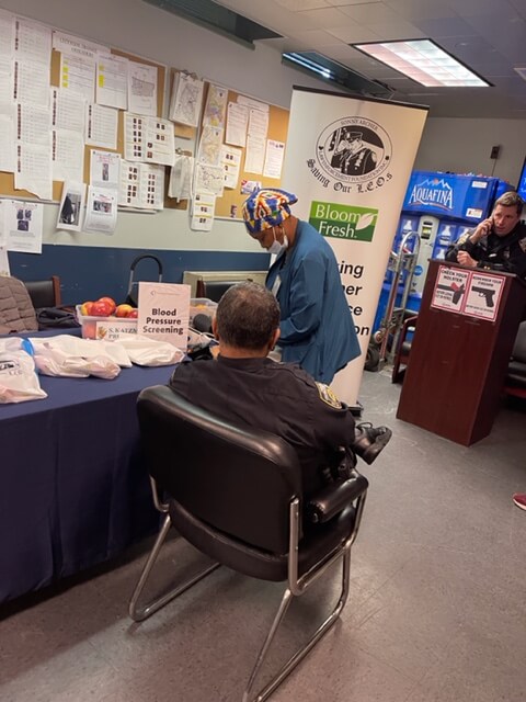 Volunteer checking a seated man's blood pressure, side view