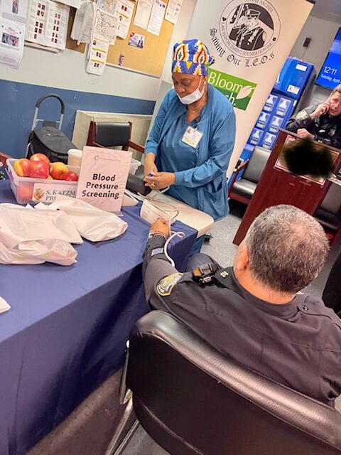 Volunteer checking a visitor's blood pressure at a station