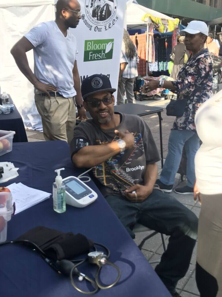 Volunteer screening a man at an outdoor table