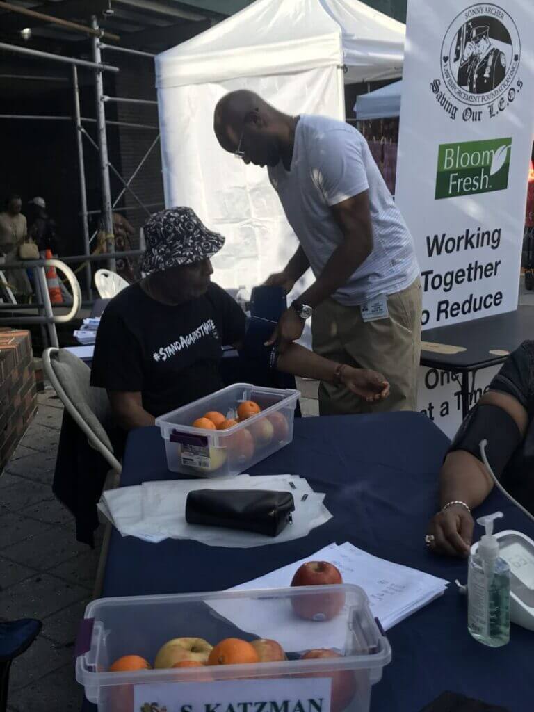 Volunteer checking blood pressure at an outdoor tent