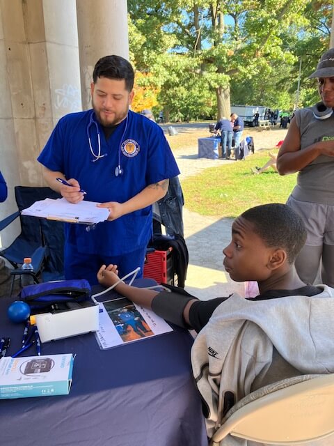 Volunteer screening a visitor under a pavilion