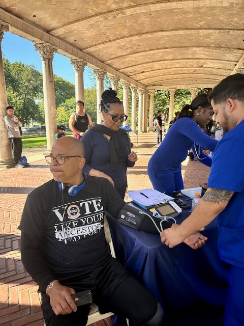 Volunteers screening visitors under a pavilion