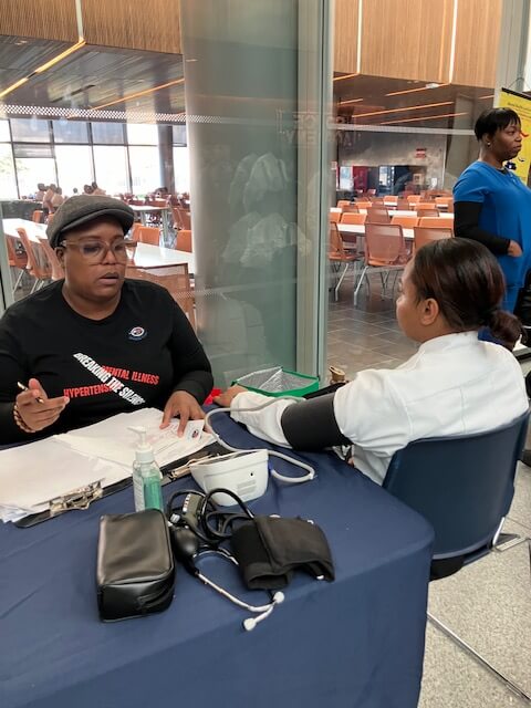 Volunteer checking a man's blood pressure in a station