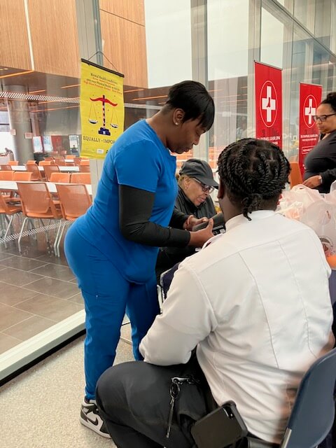 Nurse checking a visitor's blood pressure by a railing