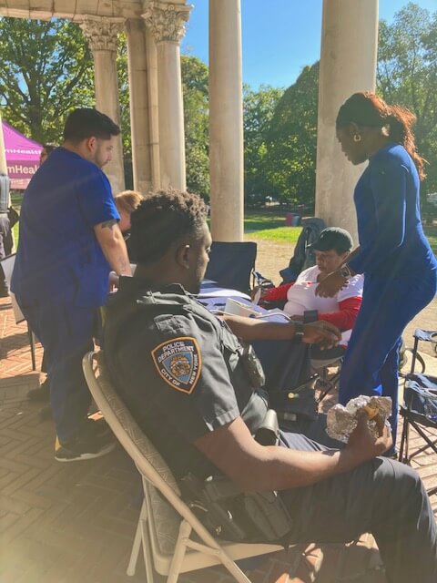 Volunteer screening a seated visitor outdoors